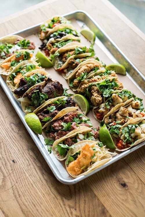 A tray of assorted tacos with lime wedges at bartaco